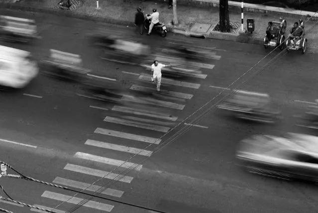 “Traffic Management”. A man fearlessly crosses a busy street in HCMC, Vietnam. Photo location: Ho Chi Minh City, Vietnam. (Photo and caption by Frederik van den Berg/National Geographic Photo Contest)