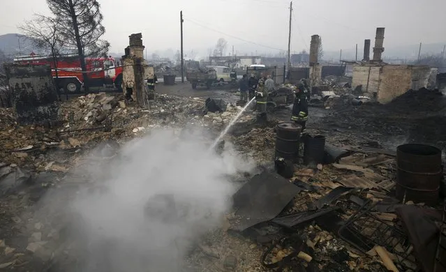 Firefighters work amidst the debris of a burnt building in the settlement of Shyra, damaged by recent wildfires, in Khakassia region, April 13, 2015. (Photo by Ilya Naymushin/Reuters)