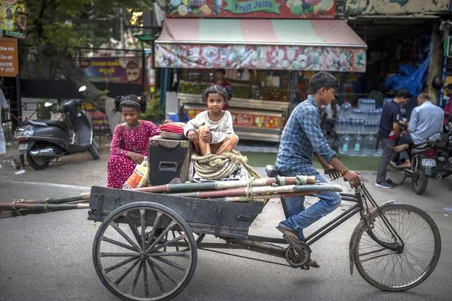 Young girls ride a cycle load carrier in New Delhi, India, Tuesday, August 17, 2021. (Photo by Altaf Qadri/AP Photo)