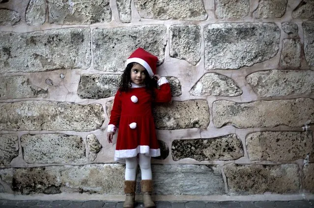 A Palestinian Greek Orthodox Christian girl dressed in Santa Claus stands outside the Saint Porfirios church in Gaza City on December 22, 2013, as preparations for Christmas celebrations get underway. (Photo by Mohammed Abed/AFP Photo)