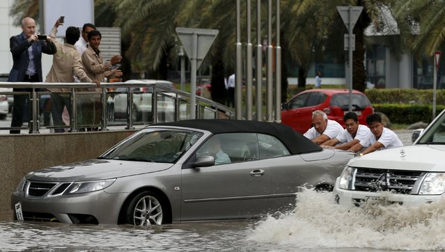 People push a car through flood waters during a rain storm in Dubai March 9, 2016. (Photo by Ahmed Jadallah/Reuters)