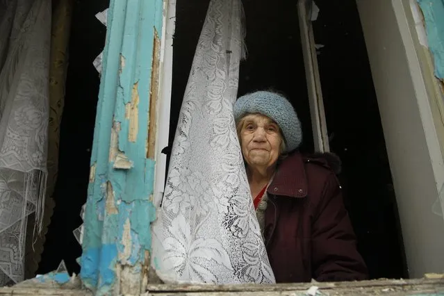 An elderly woman looks from her damaged flat after artillery shook Donetsk, eastern Ukraine, late Friday, February 3, 2017.  Heavy shelling hit both government- and rebel-controlled areas of eastern Ukraine as fighting continues Friday, and international monitors issued a sharp call for the sides to still their guns. (Photo by Alexander Ermochenko/AP Photo)