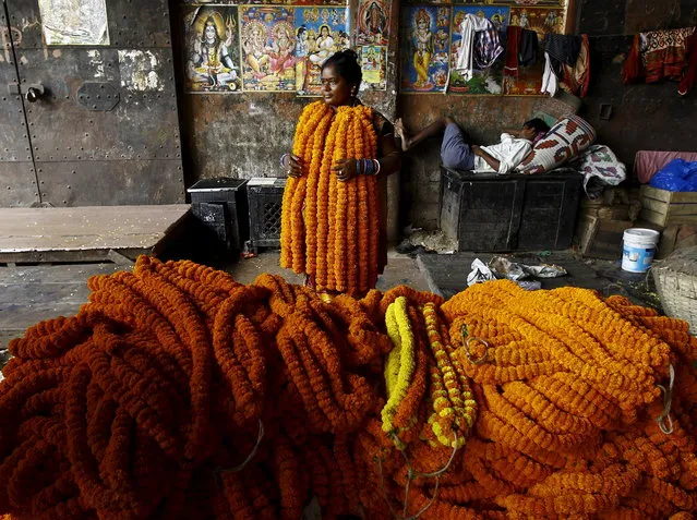A woman selling garlands of marigold flowers waits for customers at a wholesale flower market during Durga Puja festival in Kolkata October 20, 2015. (Photo by Rupak De Chowdhuri/Reuters)