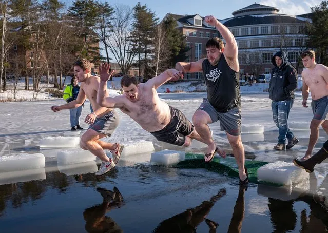Alex Sun, left, Peter Simplicio and Matt Connelly jump through a hole in the ice into Lake Andrews on the Bates College campus, Friday, February 9, 2024, in Lewiston, Maine. The annual Bates College Puddle jump started 50 years ago as a Winter Carnival tradition. (Photo by Andree Kehn/AP Photo)