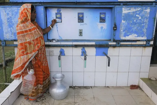 A villager collects drinking water from a water desalination plants in Bonbibi Tala in Satkhira, Bangladesh on October 5, 2021. Salinity in soil has increased by 26% over the past 35 years, and continues to do so every year. Officials working in the Shyamnagar region admit that paucity of funds was preventing the government from building new desalination plants that would convert saltwater to fresh water. (Photo by Mahmud Hossain Opu/AP Photo)