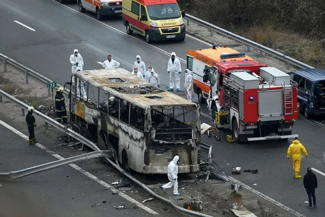 Officials work at the site of a bus accident, in which at least 46 people were killed, on a highway near the village of Bosnek, south of Sofia, on November 23, 2021. 46 people, including a dozen minors, were killed after a bus caught fire south of the Bulgarian capital early on November 23, 2021, officials said, in the country's deadliest road accident in years. (Photo by Nikolay Doychinov/AFP Photo)