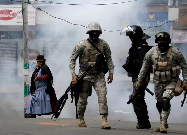 A woman walks past near riot policemen during clashes with coca growers from Yungas in La Paz, Bolivia February 21, 2017. (Photo by David Mercado/Reuters)