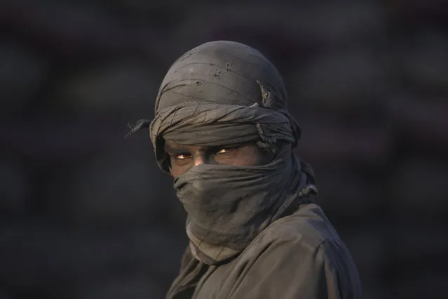An Afghan laborer pauses as he works at a charcoal shop on the outskirts of Kabul, Afghanistan, Wednesday, November 26, 2014. In the winter, prices of wood and charcoal rise among all other necessities for Afghans. (Photo by Rahmat Gul/AP Photo)