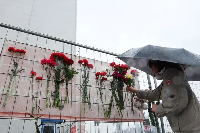 A person places flowers at a makeshift memorial in front of the Crocus City Hall, a day after a gun attack in Krasnogorsk, outside Moscow, on March 23, 2024. - Gunmen who opened fire at a Moscow concert hall killed more than 60 people and wounded over 100 while sparking an inferno, authorities said on March 23, 2024, with the Islamic State group claiming responsibility. (Photo by AFP Photo/Stringer)
