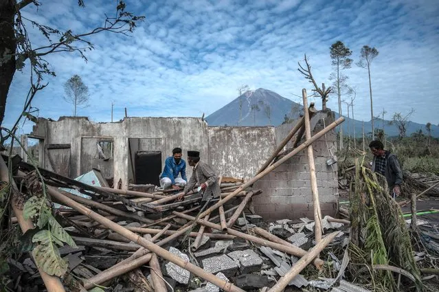 Villagers salvage their belongings from their damaged home at Curah Kobokan village in Lumajang on December 8, 2021, after Mount Semeru volcano eruption that killed at least 34 people. (Photo by Juni Kriswanto/AFP Photo)