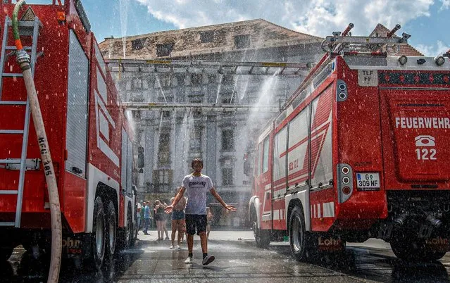 Firemen constructed a water wall for people in Graz, Austria to cool down during the heat wave on June 27, 2019. (Photo by APA PictureDesk GmbH/Shutterstock)