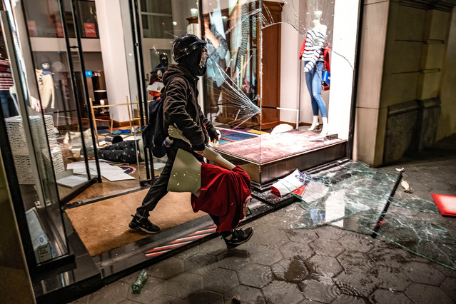 Looters are seen leaving the stores on Passeig de Gràcia taking a large number of articles of clothing during the demonstration in Barcelona, Spain on February 20, 2021. Fifth night of protests and riots in response to the arrest and imprisonment of rapper Pablo Hasel accused of exalting terrorism and insulting the crown for the content of the lyrics of his songs. (Photo by Paco Freire/SOPA Images/Rex Features/Shutterstock)