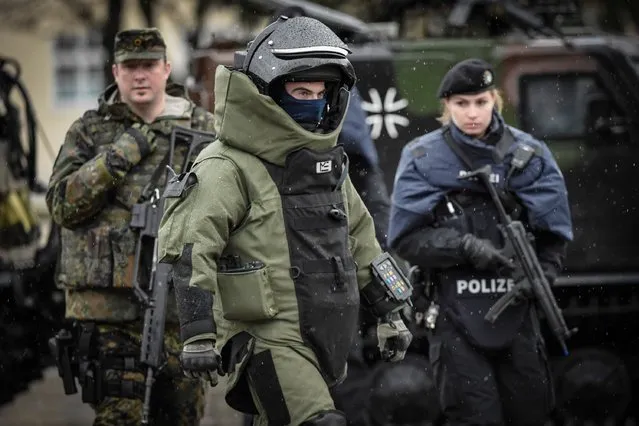 An Army EOD specialist walks by Members of the Bavarian police and the Bundeswehr, the German armed forces, during a demonstration of a dynamic operation as part of the GETEX anti-terror exercises during a media event on March 9, 2017 in Murnau, Germany. GETEX, short for the Joint Terrorism Defense Exercise, is taking place across Germany to simulate the joint operations capabilities between German law enforcement agencies and the Bundeswehr, Germany's armed forces, in battling larger-scale terror threats. (Photo by Philipp Guelland/Getty Images)