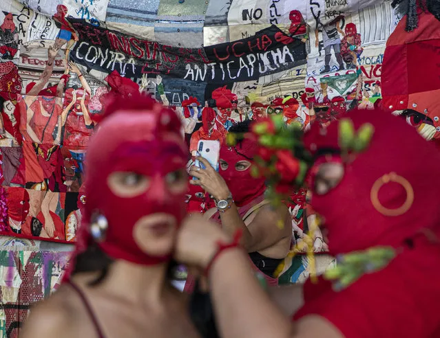 Women put on their masks while another takes a selfie prior to a march for International Women's Day in Santiago, Chile, on Monday, March 8, 2021. (Photo by Esteban Félix/AP Photo)