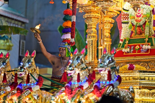 A priest offers prayer on the gold chariot bearing the idol of Hindu god Lord Murugan during Thaipusam, an annual festival representing the struggle between good and evil, on Penang Island, Wednesday, January 24, 2024. Thousands of people attended the annual procession celebrated by devotees in honor of the Hindu god to express their gratitude, fulfill vows, and perform penance. (Photo by Vincent Thian/AP Photo)