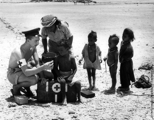 1962: RAF nursing attendant Corporal Cy Thomas treating a group of Bedouin children in the southern Arabian desert