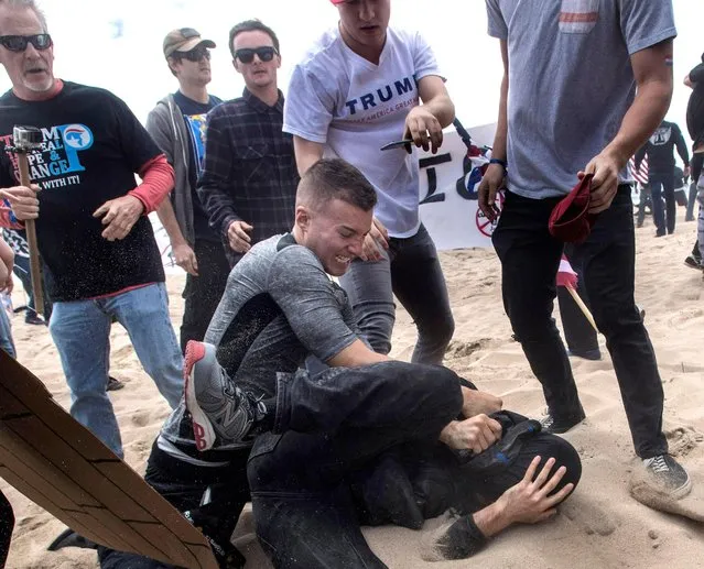 A supporter of President Donald Trump, center, clashes with an anti-Trump protester, bottom center, in Huntington Beach, Calif., on Saturday, March 25, 2017. Violence erupted when a march of about 2,000 Trump supporters at Bolsa Chica State Beach reached a group of about 30 counter-protesters, some of whom began spraying pepper spray, said Capt. Kevin Pearsall of the California State Parks Police. (Photo by Mindy Schauer/The Orange County Register via AP Photo)