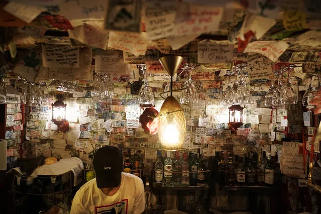 A bartender fixes a drink in a bar decorated with thousands of messages written by patrons at the Golden Gai in the Shinjuku district of Tokyo, July 26, 2019. (Photo by Jae C. Hong/AP Photo)