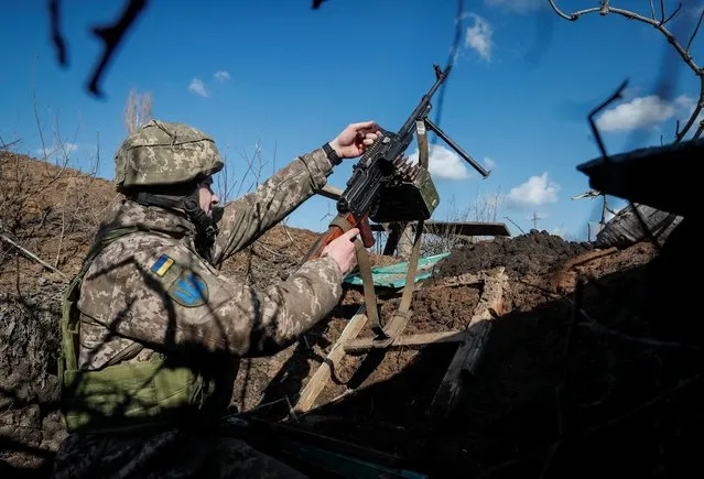 A Ukrainian service member holds a machine gun in a trench at a position on the front line near the village of Travneve in Donetsk region, Ukraine on February 21, 2022. (Photo by Gleb Garanich/Reuters)