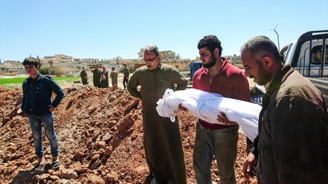 Syrians bury the bodies of victims of a a suspected toxic gas attack in Khan Sheikhun, a nearby rebel- held town in Syria’s northwestern Idlib province, on April 5, 2017 International outrage is mounting over a suspected chemical attack that killed scores of civilians in Khan Sheikhun on April 4, 2017. .Warplanes had carried out a suspected toxic gas attack that killed dozens people including several children, a monitoring group said. .The Syrian Observatory for Human Rights said those killed in the town of Khan Sheikhun, in Idlib province, had died from the effects of the gas, adding that dozens more suffered respiratory problems and other symptoms. (Photo by Fadi Al-Halabi/AFP Photo)