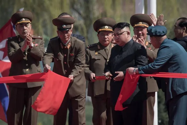 North Korean leader Kim Jong-Un (C) cuts the ribbon during an opening ceremony for “Rymoyong street”, a new housing development in Pyongyang, on April 13, 2017. With thousands of adoring North Koreans looking on – along with invited international media – Kim Jong-Un opened a prestige housing project as he seeks to burnish his nation's image even as concerns over its nuclear capabilities soar. (Photo by Ed Jones/AFP Photo)