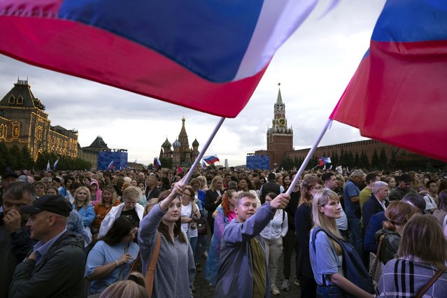 People wave Russian national flags as thousands gather on Red Square to watch a concert dedicated to the Day of Russia in Moscow, Russia, Tuesday, June 11, 2024. The Day of Russia is celebrated annually on 12 June. (Photo by Alexander Zemlianichenko/AP Photo)