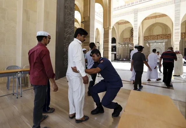 A police officer frisks a man arriving at the entrance of Bahrain Sunni Grand Mosque where joint Sunni and Shi'ites Friday prayers were held to show solidarity and co-existence between the two sects of Islam, in Juffair east  of Manama, Bahrain, July 10, 2015. (Photo by Hamad I. Mohammed/Reuters)