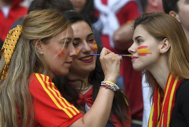 A fan has a flag painted in the colours of the Spanish flag, on her face prior to the start of the Euro 2020 soccer championship semifinal match between Italy and Spain at Wembley Stadium in London, Tuesday, July 6, 2021. (Photo by Andy Rain/Pool via AP Photo)