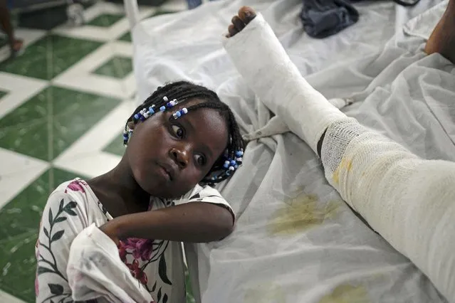 Younaika rests next to her mother Jertha Ylet, who was injured in the earthquake one week prior, at the Immaculate Conception Hospital, also known as the General Hospital of Les Cayes, Haiti, Sunday, August 22, 2021. The 7.2 magnitude quake brought down their house in Camp-Perrin, killing Ylet's father and two other relatives and seriously injuring her brother. (Photo by Matias Delacroix/AP Photo)