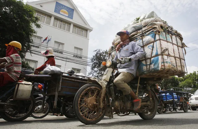 Cambodian motorists ride past the headquarters of the Cambodia National Rescue Party (CNRP), in Phnom Penh, Cambodia, Friday, May 27, 2016. A Cambodian court on Friday convicted three military commandos of beating up two CNRP lawmakers outside the parliament last year, and sentenced them to one year each in prison. The legislators' lawyer called the punishment too lenient. (Photo by Heng Sinith/AP Photo)