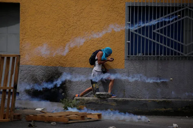 A demonstrator runs away from tear gas during a rally called by health care workers and opposition activists against Venezuela's President Nicolas Maduro in Caracas, Venezuela May 22, 2017. (Photo by Carlos Barria/Reuters)