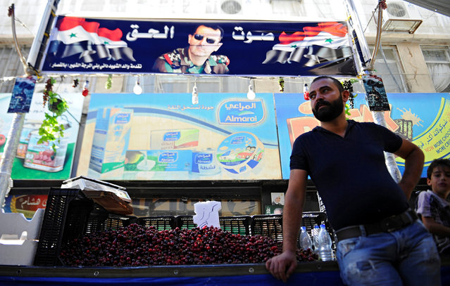 A vendor waits for customers in his stall as people shop ahead of the Muslim fasting month of Ramadan in the old Damascus, Syria, June 5, 2016. A poster depicting Syria's President Bashar al-Assad is seen in the background. (Photo by Omar Sanadiki/Reuters)