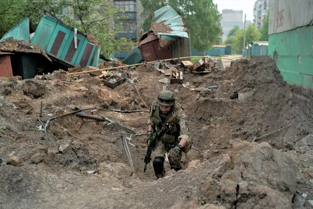 A special task force policeman inspects a site after an airstrike by Russian forces in Lysychansk, Luhansk region, Ukraine, Friday, May 13, 2022. (Photo by Leo Correa/AP Photo)