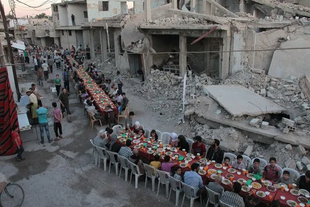 Syrian residents of the rebel-held town of Douma, on the outskirts of the capital Damascus, break their fast with the “iftar” meal on a heavily damaged street on June 18, 2017, during the Muslim holy month of Ramadan. (Photo by Hamza Al-Ajweh/AFP Photo)