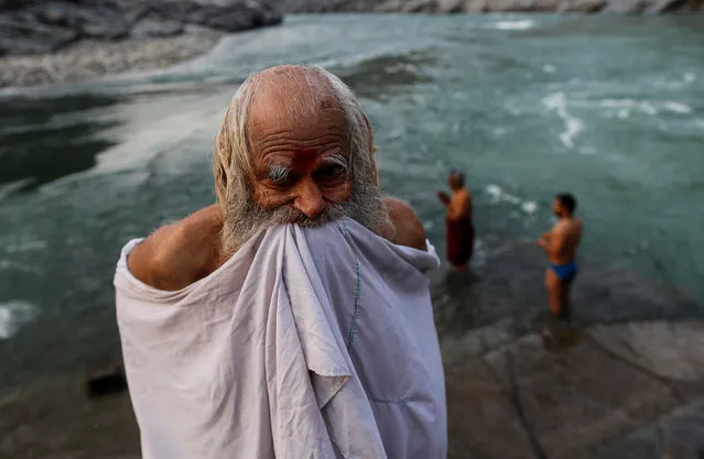 A Hindu devotee holds up his clothes after taking a dip in the river Ganges in Devprayag, India, March 29, 2017. (Photo by Danish Siddiqui/Reuters)