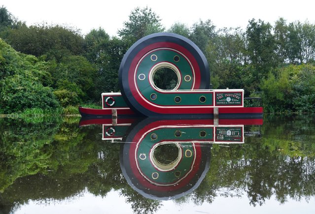 The sculpture of a canal boat after being installed on the Sheffield & Tinsley Canal on September 7, 2024. The artwork by artist Alex Chinneck measures 13 metres long and six metres high, and is fabricated from 9 tonnes of helically-rolled steel and aluminium, painted in traditional canal boat colours. The looping boat bears the name “The Industry”, after the first vessel to navigate the Sheffield & Tinsley Canal when it opened in 1819, and it features the Tudor Rose (the assay mark of Sheffield). (Photo by Owen Humphreys/PA Wire)
