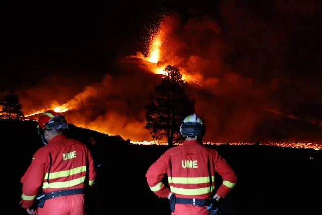 This handout picture released by the Spanish Military Emergency Unit (UME) shows UME members monitoring the lava flow produced by the Cumbre Vieja volcano, in the northern area of the Canary island of La Palma on the night of October 1, 2021. A new flow of highly liquid lava emerged from the volcano erupting in Spain's Canary islands on October 1, 2021, authorities said, as a huge magma shelf continues to build on the Atlantic ocean. (Photo by Luismi Ortiz/UME/AFP Photo)