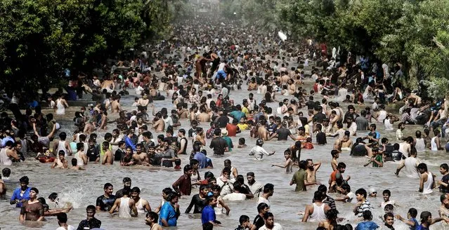 People swim in a canal to cool off as temperatures reach 111.2 degrees Fahrenheit (44 °C)  in Lahore, Pakistan on June 17, 2012