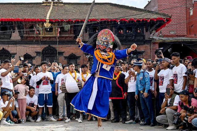 Hindu devotees watch as a masked dancer locally known as “Sawa Bhaku” performs during a procession to mark 'Indra Jatra' festival in Kathmandu on September 17, 2024. (Photo by Prakash Mathema/AFP Photo)