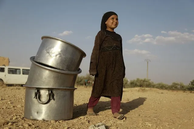 An Syrian girl stands next to cooking pots as US-backed Kurdish and Arab fighters advance into the Islamic State (IS) jihadist's group bastion of Manbij, in northern Syria, on June 23, 2016. Backed by air strikes by the US-led coalition bombing IS in Syria and Iraq, fighters with the Syrian Democratic Forces (SDF) alliance entered Manbij from the south, a monitoring group said. (Photo by Delil Souleiman/AFP Photo)