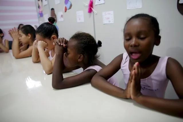 Young girls pray after taking ballet lessons at the New Dreams dance studio in the Luz neighborhood known to locals as Cracolandia (Crackland) in Sao Paulo, Brazil, August 14, 2015. (Photo by Nacho Doce/Reuters)