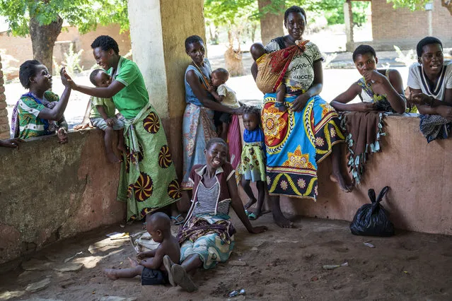 In this photo taken Wednesday, December 11, 2019, residents of the Malawi village of Tomali wait to have their young children become test subjects for the world's first vaccine against malaria. Babies in three African nations are getting the first and only vaccine for malaria in a pilot program. World health officials want to see how well the vaccine works in Malawi, Ghana and Kenya before recommending its wider use. (Photo by Jerome Delay/AP Photo)