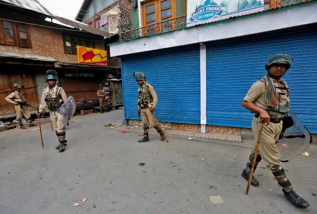 Indian policemen stand guard in front of the closed shops during a curfew in Srinagar July 13, 2016. (Photo by Danish Ismail/Reuters)