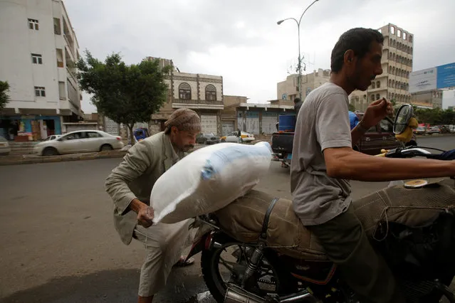 A worker carries a sack of wheat outside a store in Sanaa, Yemen, July 13, 2016. (Photo by Mohamed al-Sayaghi/Reuters)