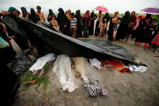 People cover the bodies of Rohingya refugee women and children who died after their boat capsized while crossing the border through the Bay of Bengal, at Shah Porir Dwip, near Teknaf, Bangladesh, August 31, 2017. (Photo by Mohammad Ponir Hossain/Reuters)