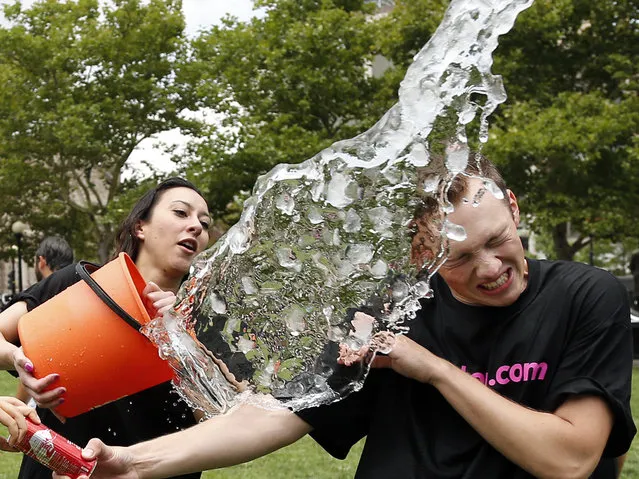 Beryl Lipton, left, douses Matt Lee during the ice bucket challenge at Boston's Copley Square, Thursday, August 7, 2014 to raise funds and awareness for ALS. The idea is: pay up for charity or get doused. The fund-raising phenomenon is catching on fast, propelled by popular videos of the dunkers and the dunked – including famous athletes and entertainers – posted on social media sites. (Photo by Elise Amendola/AP Photo)