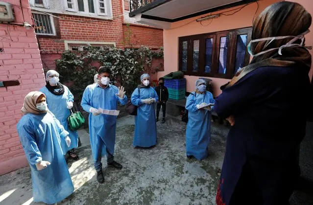 Members of a medic team wearing protective suits give information to the residents about coronavirus disease (COVID-19) during an awareness campaign in Srinagar March 19, 2020. (Photo by Danish Ismail/Reuters)