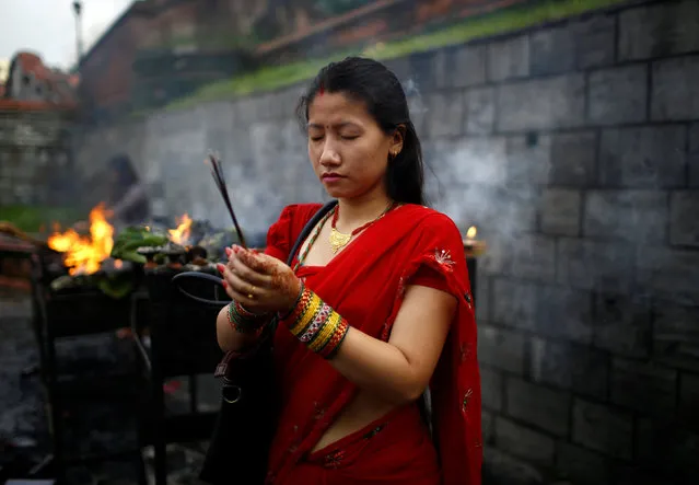 A woman holds incense sticks as she offers prayers at Pashupatinath temple to mark the Shrawan Sombar festival in Kathmandu, Nepal, July 18, 2016. (Photo by Navesh Chitrakar/Reuters)