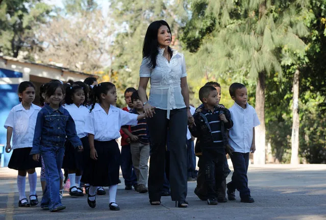 A teacher guides her pupils to the classroom on the first day of classes in Honduras, at the John F. Kennedy School in Tegucigalpa on February 8, 2010. (Photo by Orlando Sierra/AFP Photo)