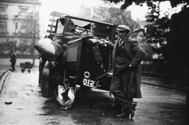 A driver leaning on his wrecked lorry, after he collided, and destroyed, a bollard in Holland Park, London, 25th May 1935. (Photo by J. A. Hampton)